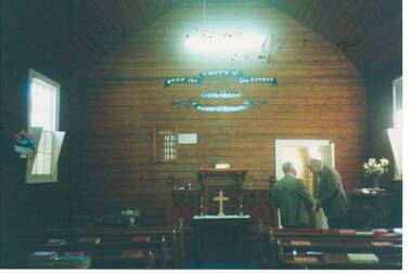 interior of church, unpainted wood-lined walls, small communion table, pews