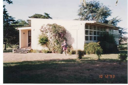 Late C20th mobile classroom, trees behind, boy standing in garden in front.
