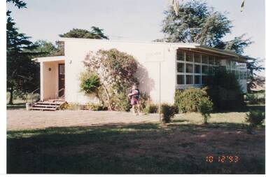Late C20th mobile classroom, trees behind, boy standing in garden in front.