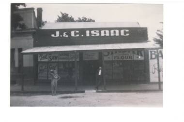 View of Grocery Store prominently displaying the name of the store as "J.& C. ISAAC" and two people visible in front of the building