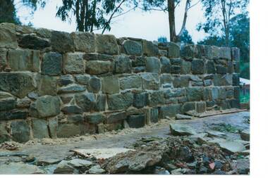 Section of completed wall, five rows of blocks high, blocks of slightly unequal shape and size.