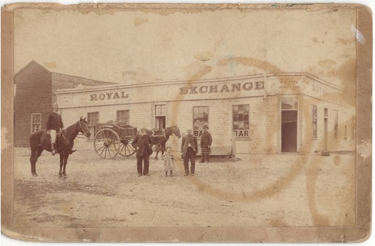 Single story weatherboard hotel on corner, "Royal Exchange" signage, hall attached left, mounted policeman,, two elderly gentlemen with young child, buggy.