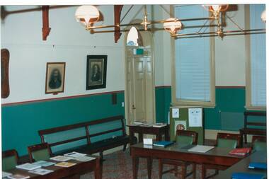 Interior Buninyong Courthouse, view to NW corner showing entrance door, tall windows with venetian blinds, hanging brass lamps.