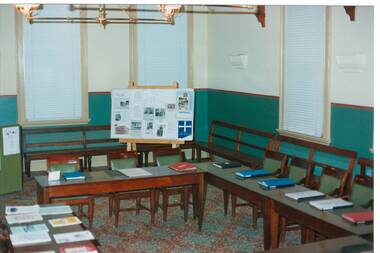 Interior Buninyong Courthouse, view to NE corner, tables with display books, display board and benches around walls.