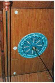 Wood-lined ceiling, with ornate, painted ceiling rose and brass support rod for lights.