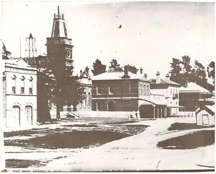 Street scene, fire station, Town Hall with clock-tower, two story brick shops, two story hotel with verandah.