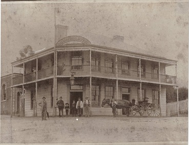 Corner hotel, weatherboard, two story, chamfered corner with main entrance, men, boys and horse and cart outside, section of brick Masonic Lodge on left