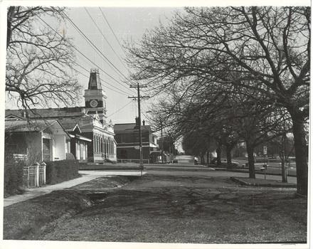 Streetscape, C20th Fire station left, C19th brick Town Hall Centre, and side of two story brick store, avenue of trees running from right to centre.