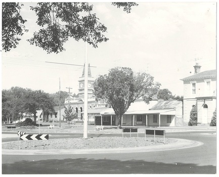 Across roundabout to Town Hall, offices and fire station left, Butcher shop and Adams Store, and two story Bank.