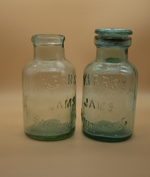 Two glass jam jars, one with chipped rim, one with lid