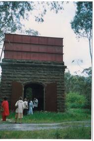 Water tower, 6m high square bluestone base with arched double door, riveted iron tank three horizontal sections above.