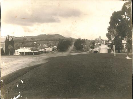View of township across unmade road which leads uphill towards mountain.