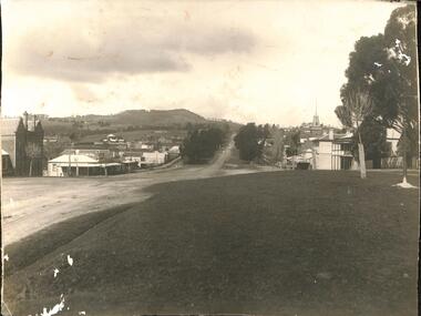 View of township across unmade road which leads uphill towards mountain.