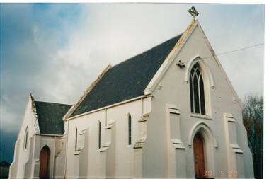 White rendered church, side view, buttresses, gothic windows and door frames, slate roof.