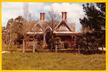 Colour photograph of "Clifton Villa" showing the front entrance and garden. Part of the iron work on the verandah, two of the gables and four of the iconic chimneys are visible