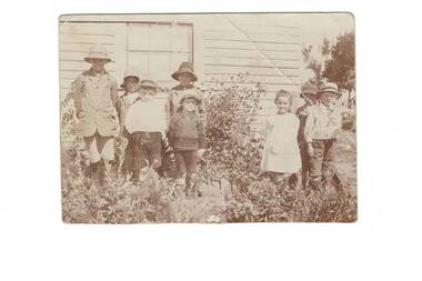 Group of eight school children in garden outside Mount Mercer Primary School circa 1920