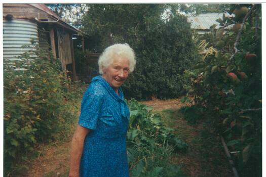 May Williams aged 91 in her garden at Scotsburn: vegetables and fruit trees in the foreground, outbuildings visible at rear.