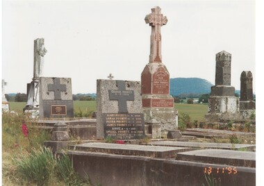 View of graves, tombstones and monuments, mountain in background.