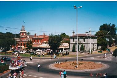 View across roundabout, victorian buildings, truck/float end of procession