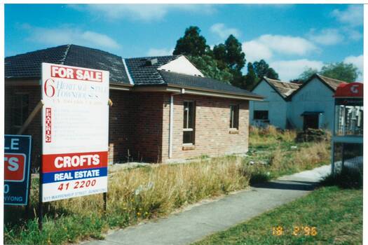 Photograph of new building replacing earlier cottage on site, sign advertising 6 heritage style townhouses visible in foreground