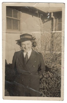 Young woman in WRAN uniform  in front of corrugated iron building.