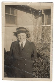 Young woman in WRAN uniform  in front of corrugated iron building.