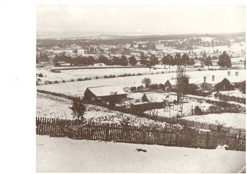 Winter landscape scene showing buildings, fences, and trees