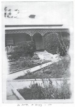 Part of the front of the house is visible showing the lacework on the front verandah and the pathways in part of the garden