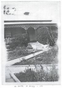 Part of the front of the house is visible showing the lacework on the front verandah and the pathways in part of the garden