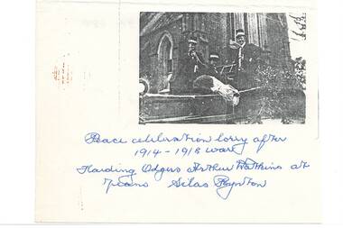 Three men in uniform standing in lorry tray in front of church.