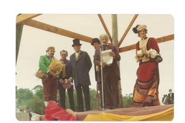 Characters in Victorian costumes standing on outdoor stage