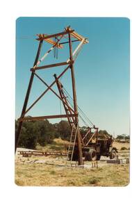 very tall log frame being raised with a crane in a park