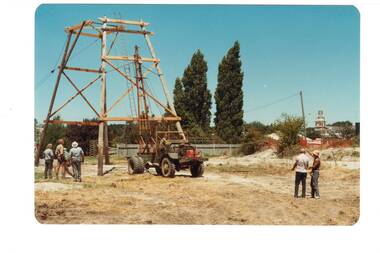 Partly constructed log poppet head with small portable crane, two groups of workmen.