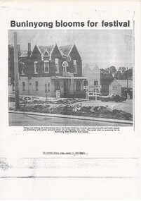 newspaper report, photo of corner hotel, two-story brick, traffic island in foreground filled with planted flowers.