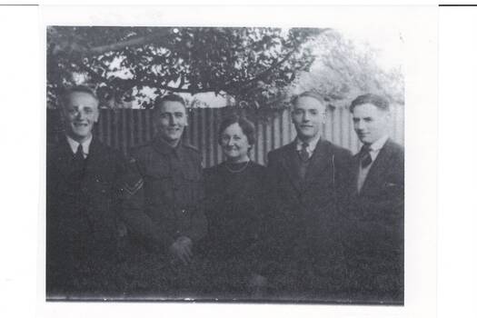 Family group, middle aged lady centre in dark dress, two young men either side, three in suits, one in uniform.