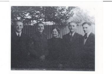 Family group, middle aged lady centre in dark dress, two young men either side, three in suits, one in uniform.