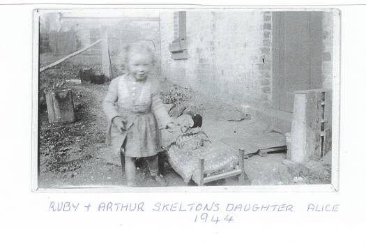 Skelton family photograph with child, showing part of cottage and garden.