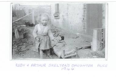 Skelton family photograph with child, showing part of cottage and garden.
