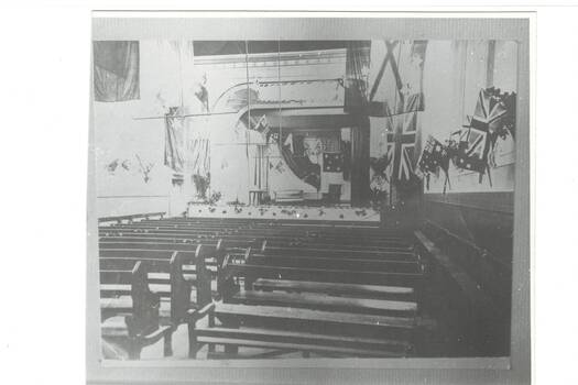Interior of Buninyong Townhall circa 1919 set up for a community event complete with multiple flags and church pews possibly to commemorate those who served in World War 1