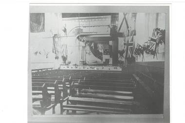 Interior of Buninyong Townhall circa 1919 complete with multiple flags and church pews possibly to commemorate those who served in World War 1