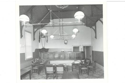 Large room, high wooden ceiling, suspended lamps, tables and chairs set out.