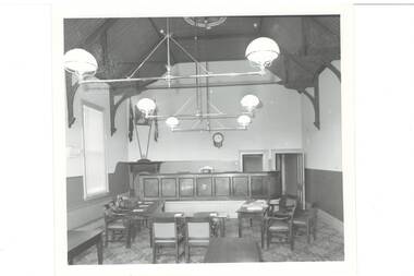 Large room, high wooden ceiling, suspended lamps, tables and chairs set out.