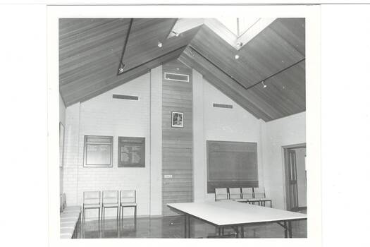 Large modern foyer, high peaked wooden ceiling with large skylight, table and several chairs.