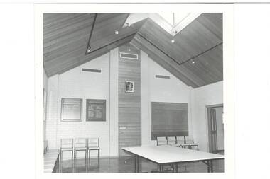 Large modern foyer, high peaked wooden ceiling with large skylight, table and several chairs.