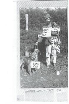 Man in swagman's costume, covered with signs, holding a dog on lead. 