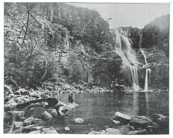 Waterfall, three drops over cliff to pool, fallen rocks around base of cliff, some scrubby plant-growth