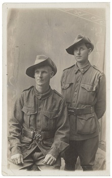 A black and white image of two unknown World War 1 Australian Soldiers in uniform, one seated, one standing