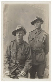A black and white image of two unknown World War 1 Australian Soldiers in uniform, one seated, one standing