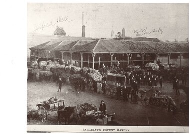 Black and white picture of two storey building surrounded by horse drawn carts filled with produce and a number of people posing for the photographer