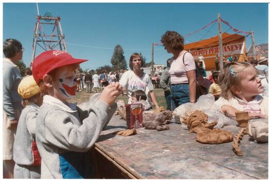 Close-up, children modelling clay, two adults supervising, outdoors, poppet head in background.